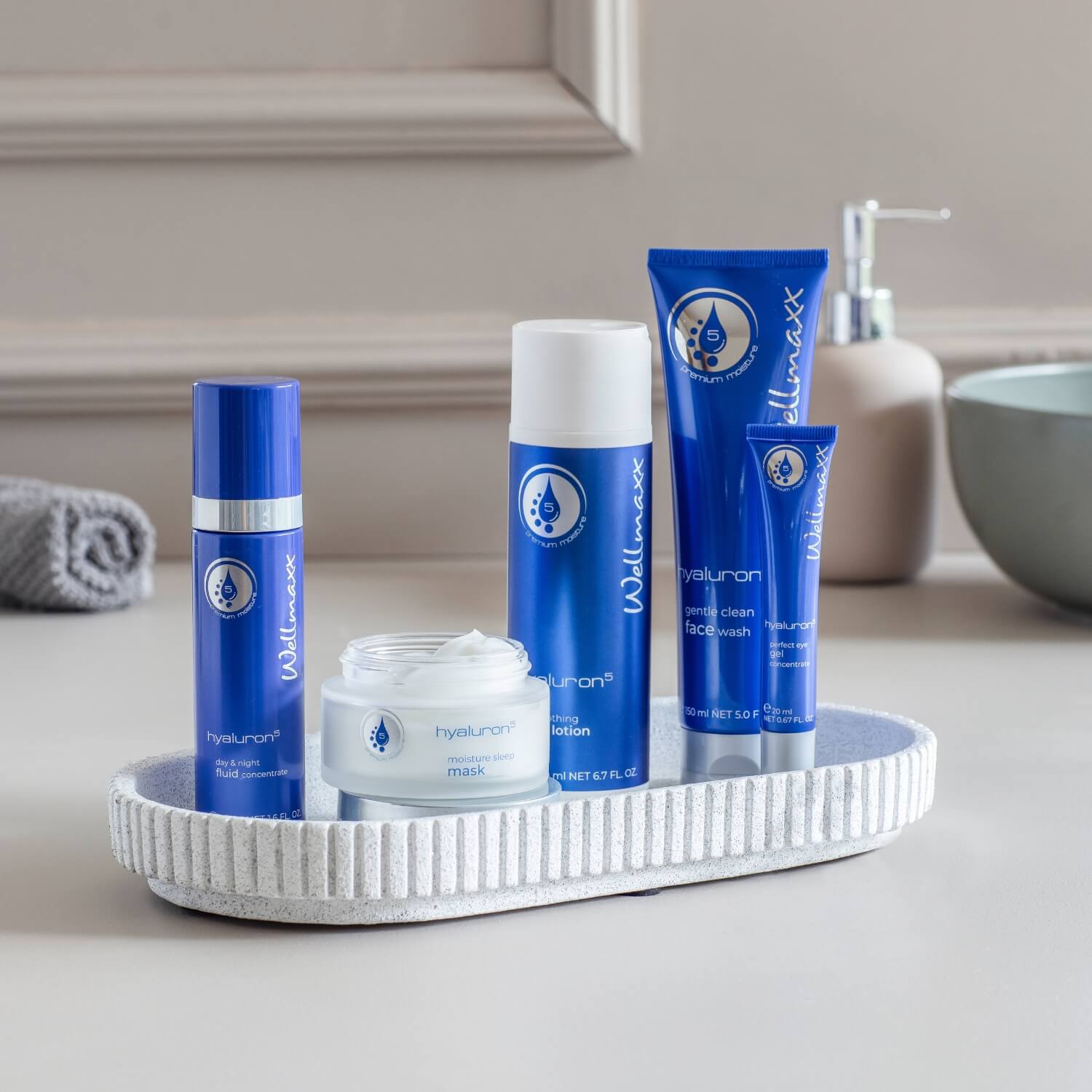 WELLMAXX Pflegeprodukte der Serie hyaluron⁵ dekorativ arrangiert.
