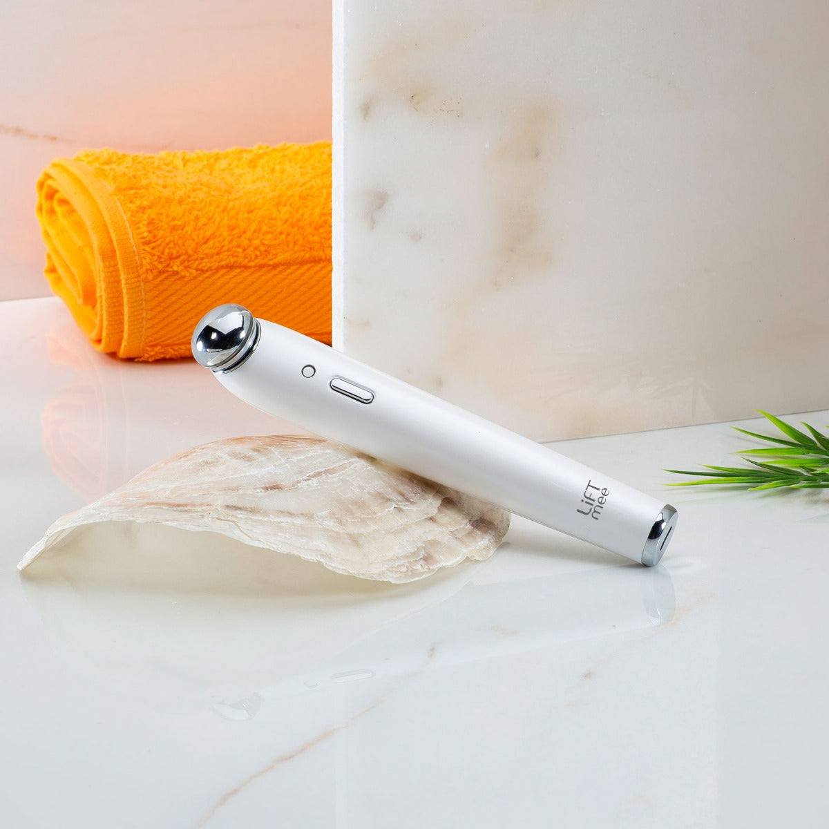 LiFTmee ionic + beauty light auf einer Muschel liegend. Mamorwand und Handtuch im Hintegrrund