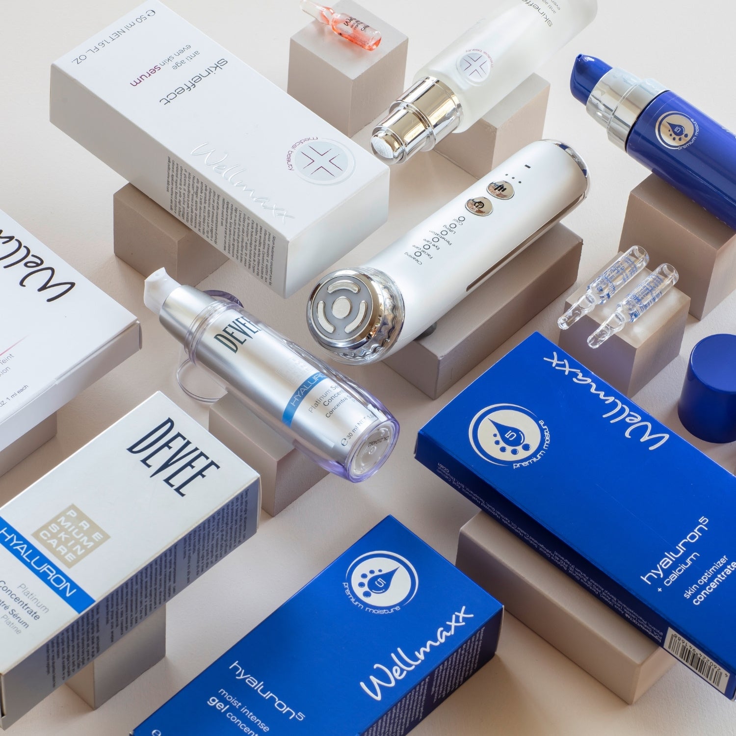 Moodaufnahme verschiedener liegender WELLMAXX, DEVEE und LiFTmee Produkte auf beigen Holzklötzchen. Aus der Vogelperspektive fotografiert.